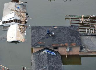 Stranded New Orleans residents sit on their roof in the wake of the Katrina disaster (Jocelyn Augustino)