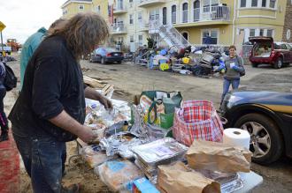 Residents in the Rockaways collect donated food items in a wreckage-strewn street (Karen Blumberg)