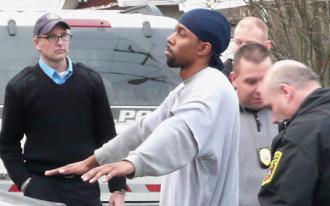 Police officers surround a young Black suspect