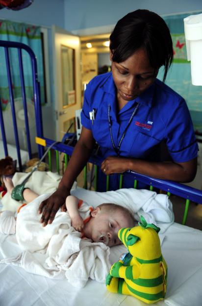A nurse cares for a seven-month-old at a National Health Service hospital in London
