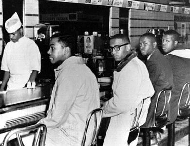 Four students sit at a lunch counter in defiance of segregation