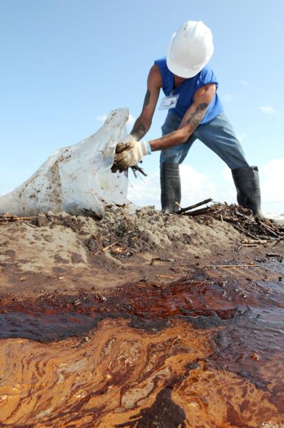 A worker attempts to clean up oil washing onto Elmer's Island, off the coast of Louisiana