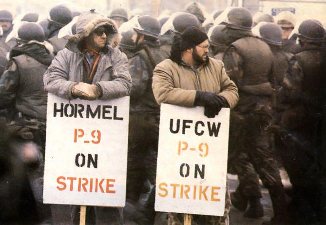 P-9 strikers on the picket line, surrounded by riot-clad National Guard troops