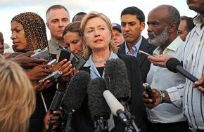 Hillary Clinton stands beside Haitian president René Préval, speaking to reporters at the airport