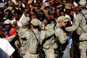 U.S. troops push back a crowd of Haitians waiting for food and water outside the Port-au-Prince airport