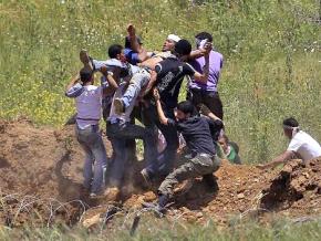 Protesters who marched to a fortified border fence with Israel carry a man wounded by IDF forces