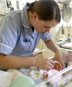 A nurse attending a patient in an NHS neonatal intensive care unit