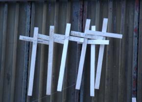Crosses adorn the border wall, with some bearing names and others saying simply "Desconocido" (unknown)