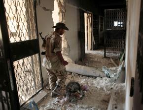A Libyan rebel in Zawiyah guards an unexploded NATO bomb