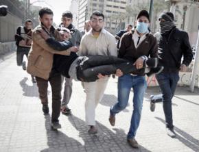 Protesters rush a wounded man away from clashes with armed forces in Cairo