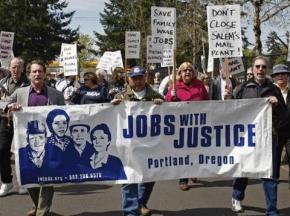 Demonstrators march to the Salem, Ore., USPS facility