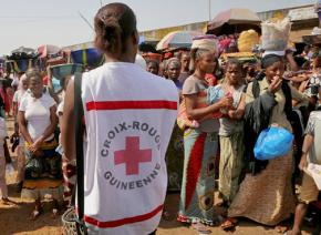 A Red Cross volunteer gives instructions about Ebola to a crowd in a city in Guinea