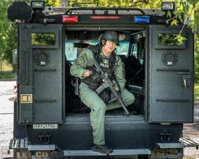 A SWAT officer poses in the back of an armored vehicle