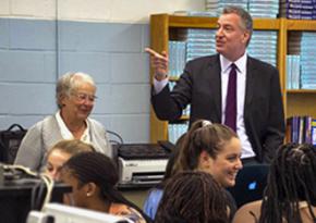 New York City Schools Chancellor Carmen Farińa (back left) and Mayor Bill de Blasio (standing) visit a school