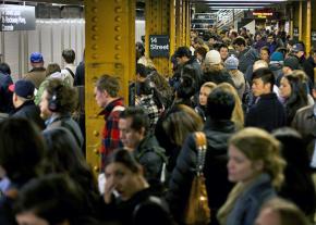 Commuters crowd onto a New York City subway platform