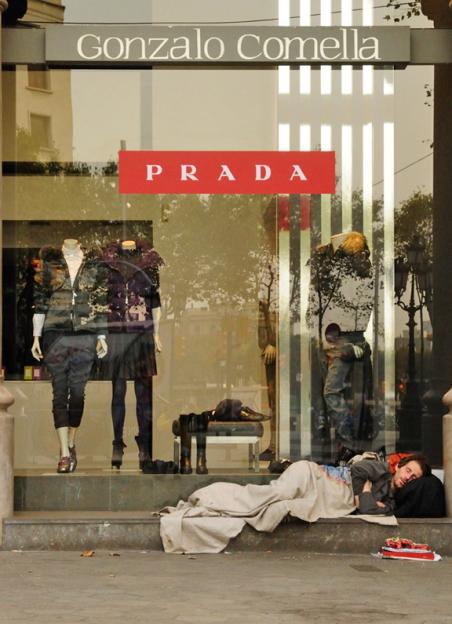 A homeless man rests outside a Prada store