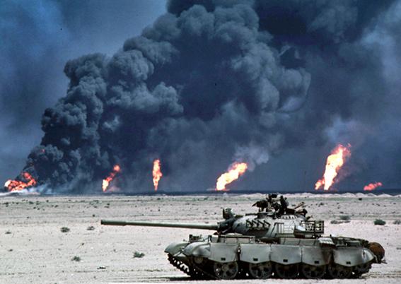 U.S. military forces roll by oil field fires in Southern Iraq in 2003