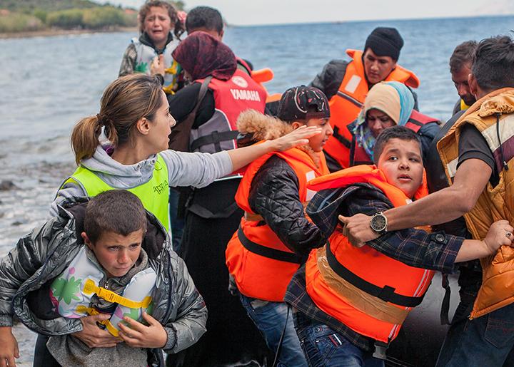 Syrian refugees are met by aid workers in Greece after crossing the Mediterranean