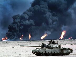 A U.S. tank rolls by a burning oil field in Iraq