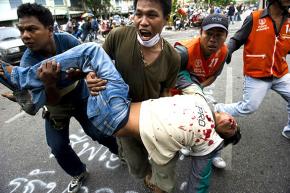 Thai Red Shirt protesters carry a man who was wounded when police opened fire