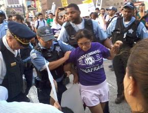 One of the undocumented youth who blocked traffic is led away by Chicago police