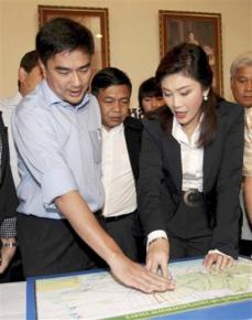 Prime Minister Yingluck Shinawatra (right) stands with conservative leader Abhisit Vejjajiva over a map of flooded areas