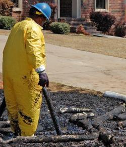 Cleanup workers try to remove oil from a front yard in Arkansas