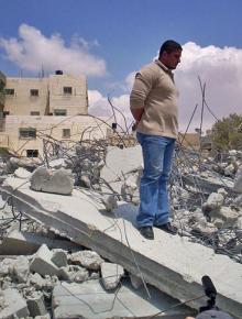 An earlier victim of home demolition stands on the remains of his house in east Jerusalem