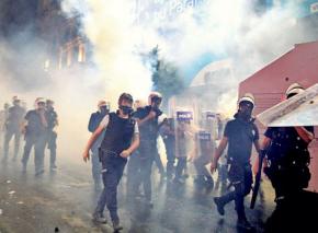 Turkish riot police march through a cloud of tear gas