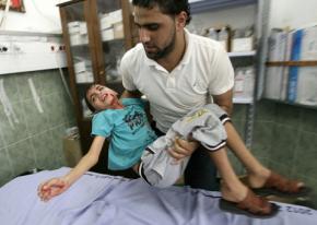 A Palestinian man brings a wounded child into a hospital
