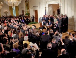 Barack Obama signs health care legislation in front of Democratic lawmakers in the East Room of the White House