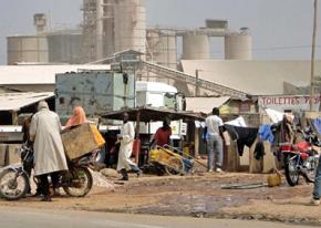 People work and trade along a dirt road outside a cement factory in Cameroon
