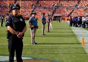 Police line the field before a capacity crowd at an NFL game