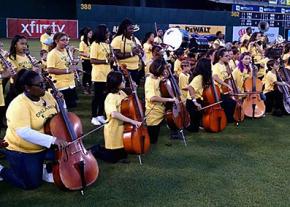 The honors band from Oakland schools kneels as they play the national anthem at an Oakland Athletics game