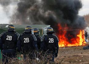 French riot police oversee the demolition of refugee shelters at a camp in Calais