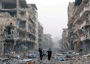 Syrian civilians walk through the rubble of the city of Deir ez-Zor