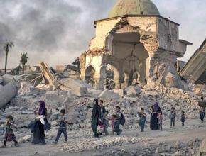 Civilians walk through the streets of Mosul after months of U.S. air strikes