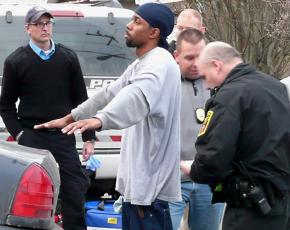 Police officers surround a young Black suspect